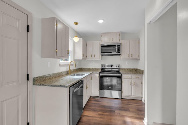 kitchen featuring dark wood-type flooring, sink, hanging light fixtures, appliances with stainless steel finishes, and light stone countertops