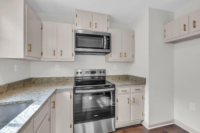 kitchen featuring appliances with stainless steel finishes, light stone countertops, dark hardwood / wood-style flooring, and white cabinets