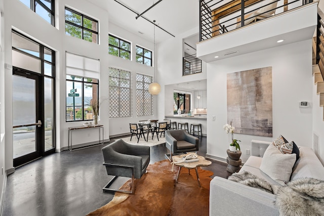 living room with concrete flooring and a towering ceiling