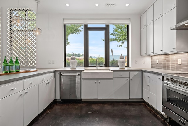 kitchen featuring pendant lighting, white cabinets, sink, decorative backsplash, and appliances with stainless steel finishes