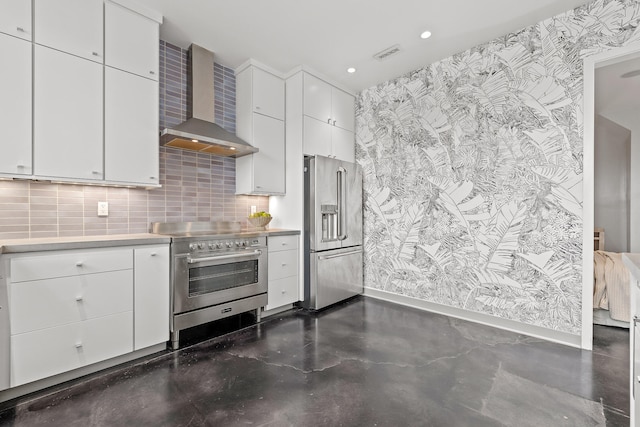 kitchen with decorative backsplash, white cabinetry, wall chimney exhaust hood, and appliances with stainless steel finishes