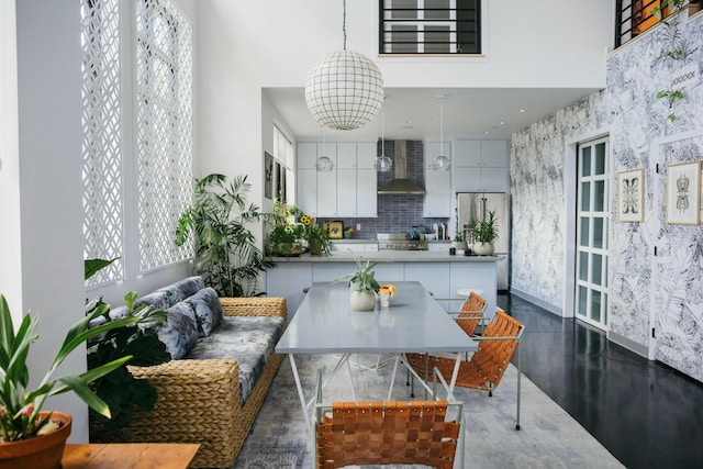 kitchen featuring a healthy amount of sunlight, wall chimney range hood, white cabinetry, and fridge