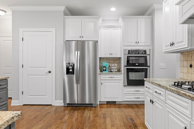 kitchen with light stone countertops, appliances with stainless steel finishes, decorative backsplash, and white cabinetry