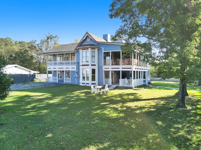 rear view of property with a balcony and a yard