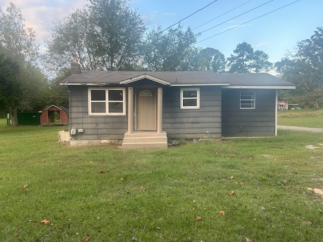 view of front facade featuring a storage unit and a front yard