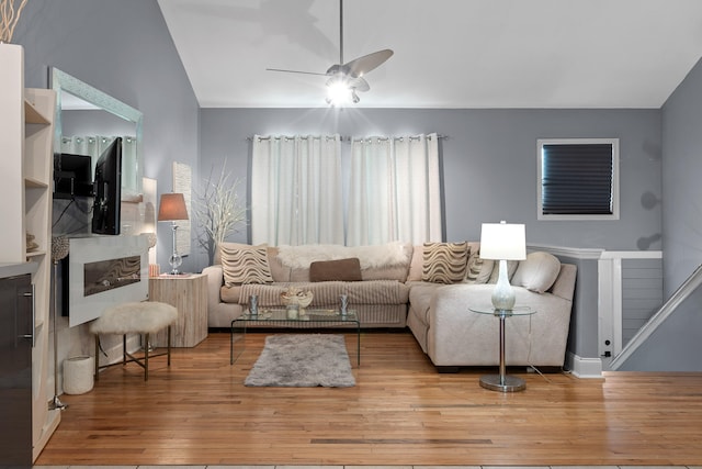 living room with light wood-type flooring, vaulted ceiling, and ceiling fan