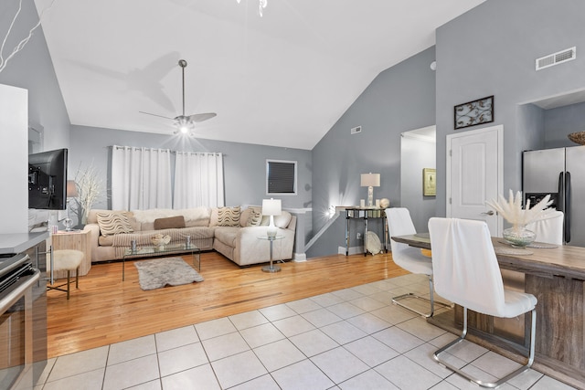 living room with ceiling fan, light hardwood / wood-style flooring, and lofted ceiling