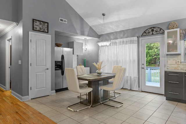 dining room with high vaulted ceiling and light wood-type flooring