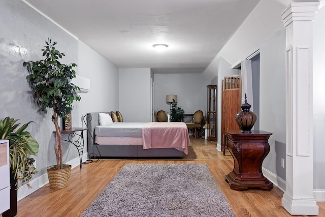 bedroom with light hardwood / wood-style flooring and a wall unit AC