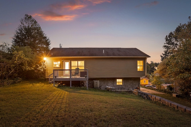 back house at dusk featuring a deck, a lawn, and central AC