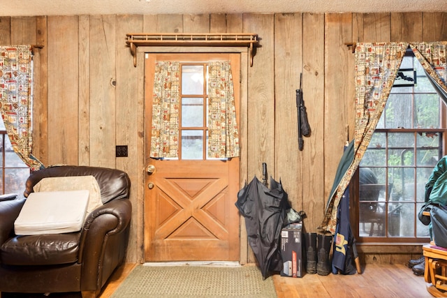 interior space with a textured ceiling, wooden walls, and light hardwood / wood-style floors