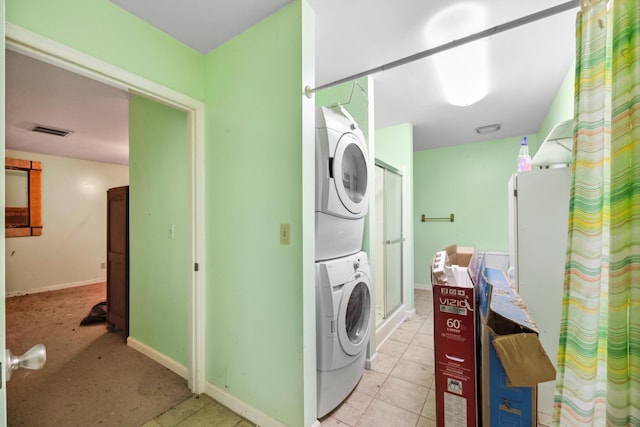 clothes washing area featuring light tile patterned floors and stacked washer / drying machine