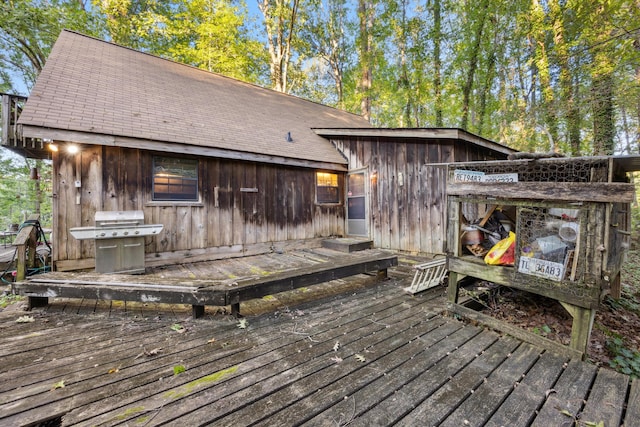 wooden deck featuring an outdoor structure and a grill