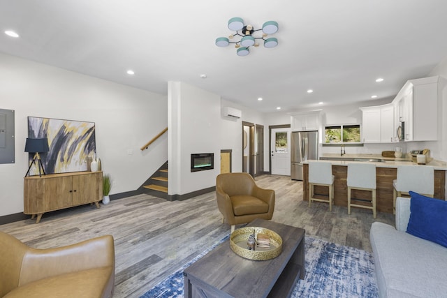 living room with an AC wall unit and light hardwood / wood-style flooring