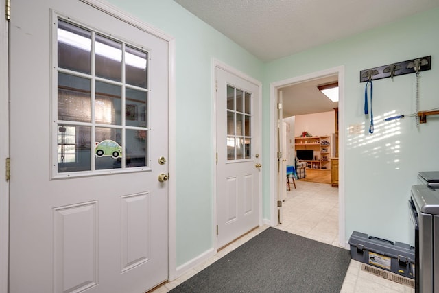 doorway to outside with a textured ceiling and light tile patterned floors