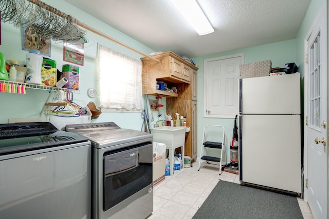 washroom with cabinets, a textured ceiling, and washing machine and clothes dryer