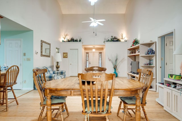 dining area featuring light hardwood / wood-style floors, a towering ceiling, and ceiling fan