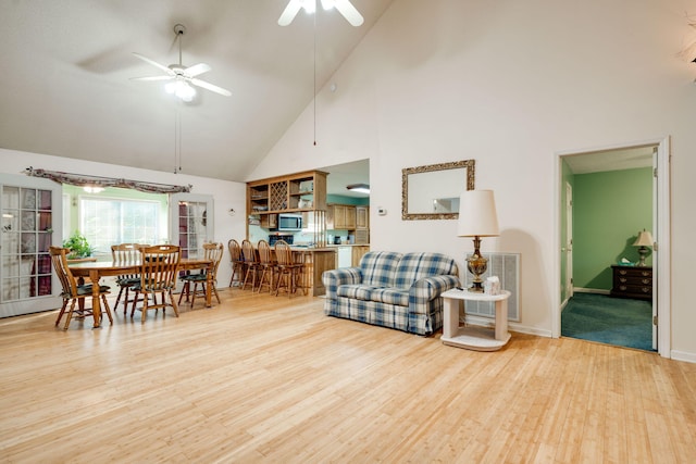 living room with ceiling fan, high vaulted ceiling, and light hardwood / wood-style floors