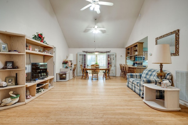 living room with light hardwood / wood-style floors, high vaulted ceiling, and ceiling fan