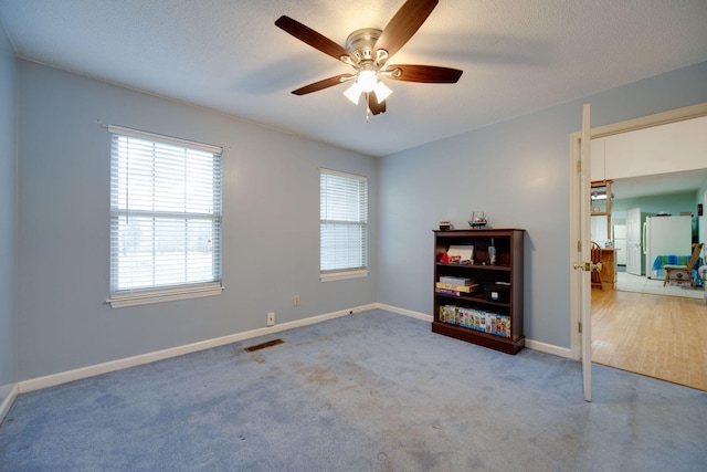 spare room featuring ceiling fan, carpet, and a textured ceiling