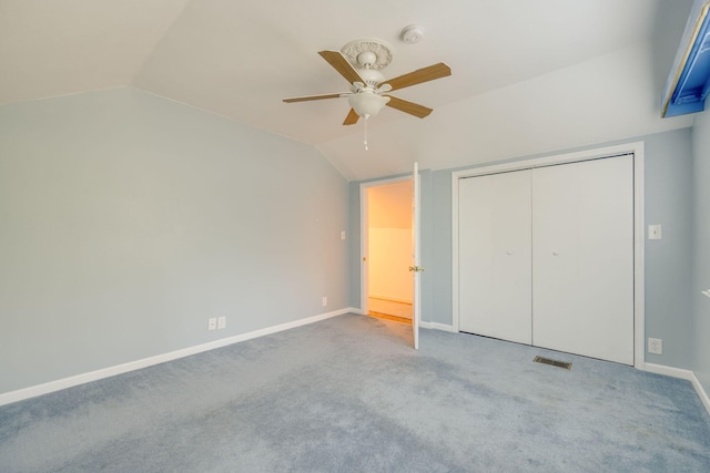 unfurnished bedroom with vaulted ceiling, carpet flooring, a closet, and ceiling fan