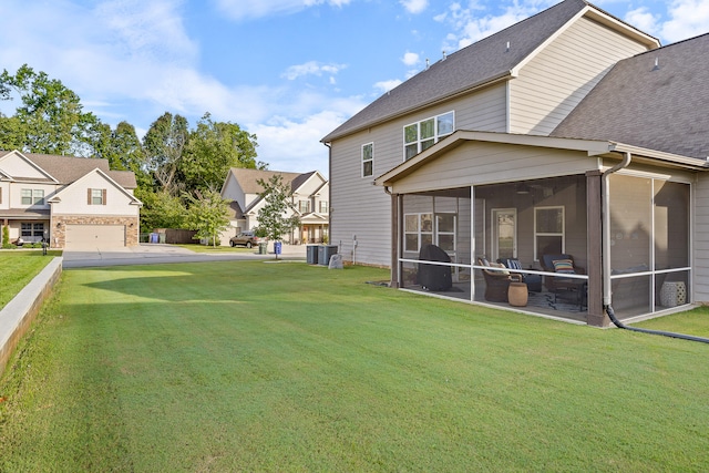 view of yard featuring cooling unit, a garage, and a sunroom