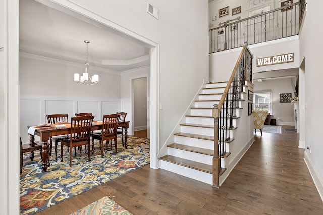 interior space featuring wood-type flooring, ornamental molding, a tray ceiling, and a notable chandelier