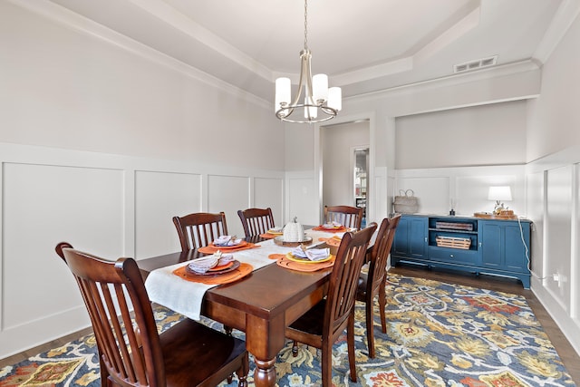 dining room with ornamental molding, a tray ceiling, a chandelier, and dark hardwood / wood-style flooring