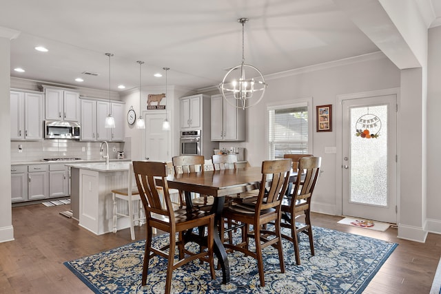 dining room featuring sink, a chandelier, dark hardwood / wood-style floors, and crown molding