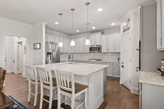 kitchen featuring light stone countertops, appliances with stainless steel finishes, hardwood / wood-style flooring, and sink