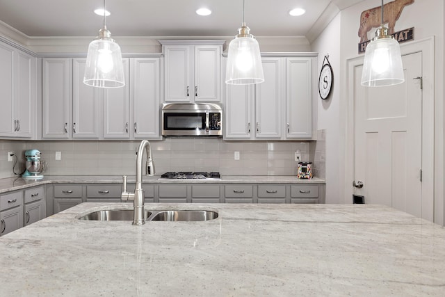 kitchen with tasteful backsplash, sink, stainless steel appliances, decorative light fixtures, and light stone countertops