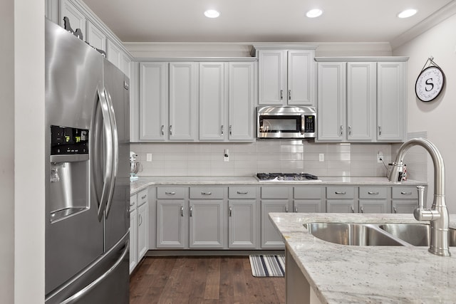 kitchen with appliances with stainless steel finishes, light stone counters, tasteful backsplash, dark hardwood / wood-style floors, and sink