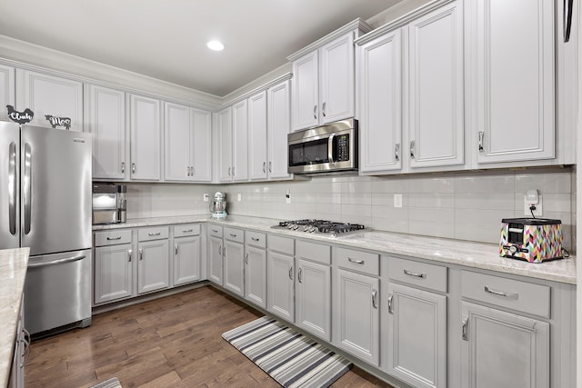 kitchen with decorative backsplash, stainless steel appliances, light stone counters, and dark hardwood / wood-style floors