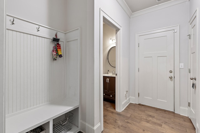 mudroom featuring sink, light wood-type flooring, and ornamental molding