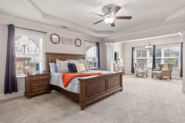 bedroom with multiple windows, a raised ceiling, and light carpet