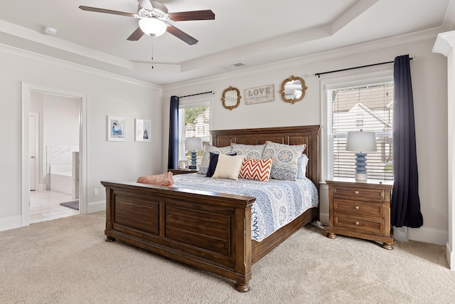 carpeted bedroom with connected bathroom, a tray ceiling, ceiling fan, and multiple windows