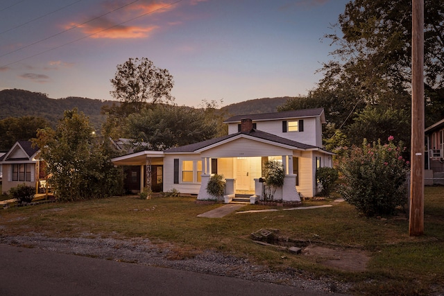 view of front of property featuring a lawn, a porch, and a mountain view