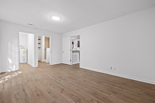 empty room with water heater and light hardwood / wood-style floors