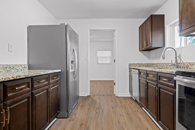 kitchen featuring light stone countertops, light hardwood / wood-style floors, appliances with stainless steel finishes, and sink