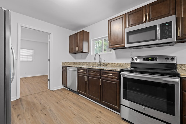 kitchen with appliances with stainless steel finishes, dark brown cabinetry, light wood-type flooring, and sink