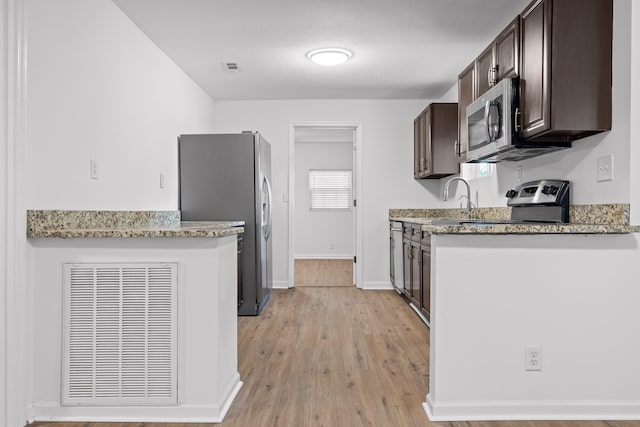 kitchen with dark brown cabinetry, light stone counters, sink, appliances with stainless steel finishes, and light hardwood / wood-style floors