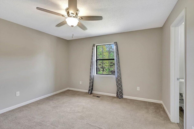 spare room featuring ceiling fan, light colored carpet, and a textured ceiling