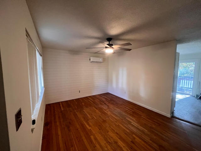 spare room with a textured ceiling, dark hardwood / wood-style flooring, a wall mounted AC, and ceiling fan