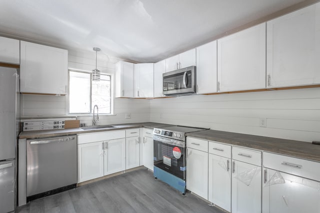 kitchen featuring dark hardwood / wood-style floors, sink, white cabinetry, stainless steel appliances, and decorative light fixtures