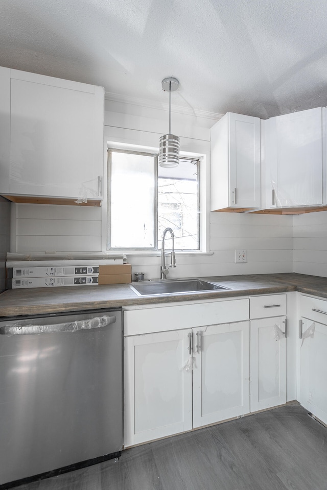 kitchen with pendant lighting, sink, white cabinets, dark hardwood / wood-style flooring, and stainless steel dishwasher