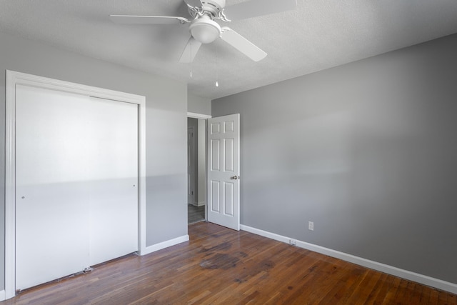 unfurnished bedroom featuring ceiling fan, a textured ceiling, a closet, and dark hardwood / wood-style flooring