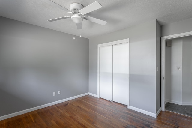 unfurnished bedroom with a closet, ceiling fan, dark hardwood / wood-style floors, and a textured ceiling