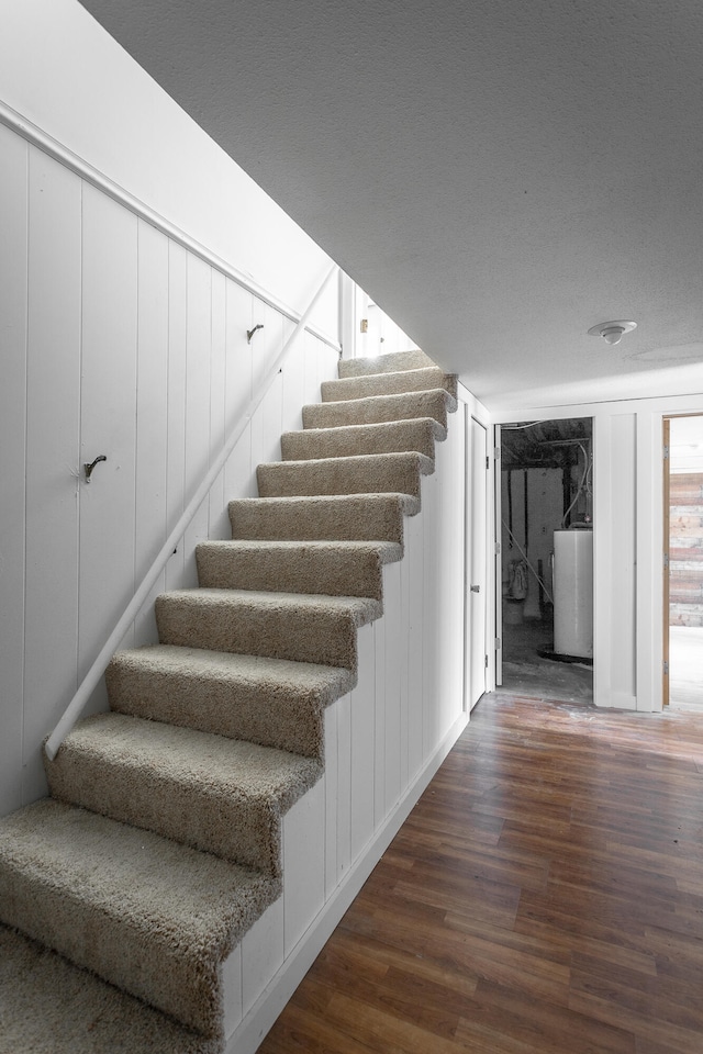 stairway featuring gas water heater, a textured ceiling, and hardwood / wood-style floors