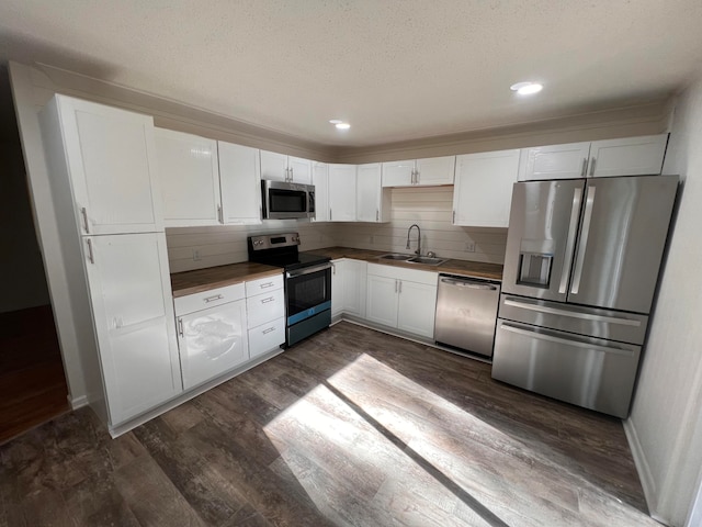 kitchen featuring white cabinetry, dark wood-type flooring, backsplash, stainless steel appliances, and sink