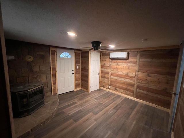 entryway with wood walls, a wall mounted AC, dark wood-type flooring, and a wood stove